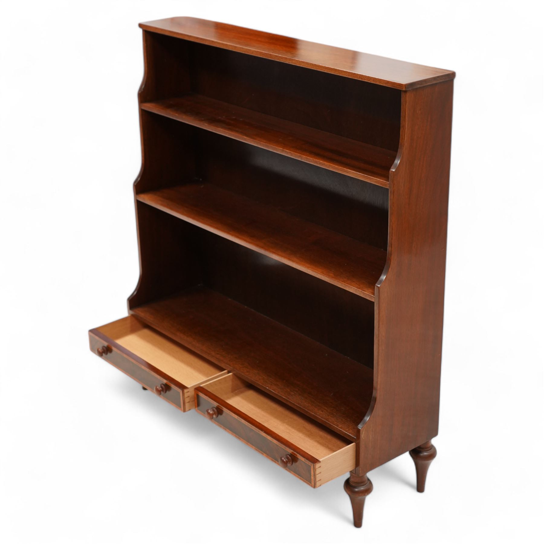 Mahogany waterfall bookcase, fitted with two fixed shelves over two drawers, the drawers with satinwood bands and turned handles, on turned tapering feet 