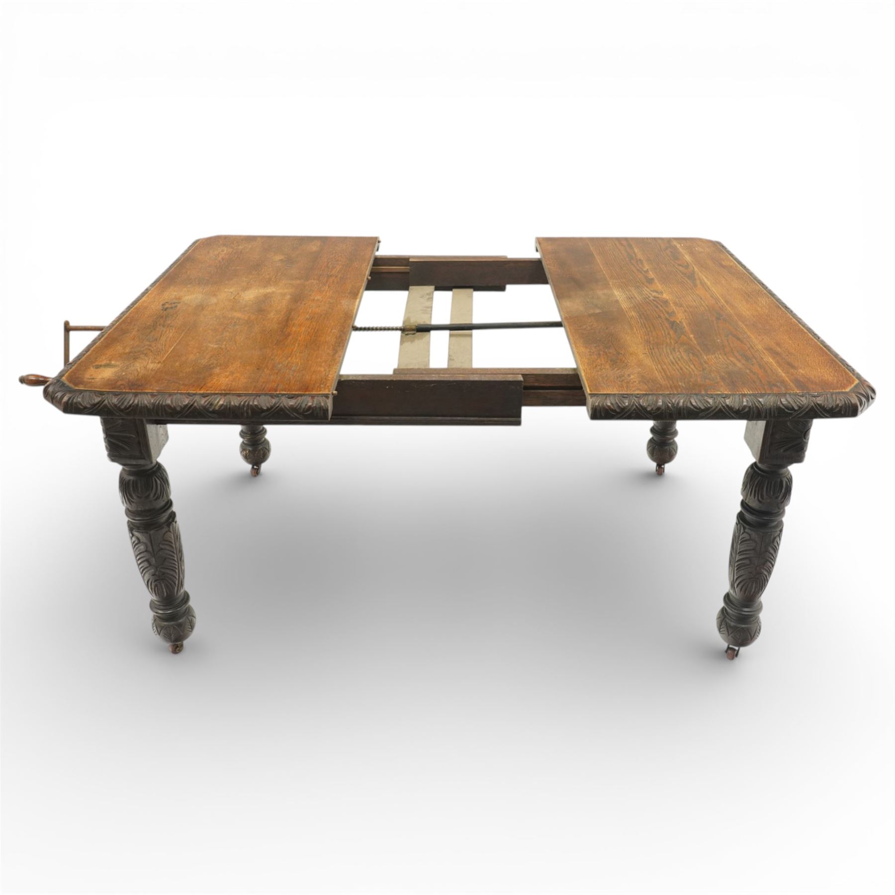 19th century heavily carved oak extending dining table, with winding mechanism and a gadrooned edge, over block and turned supports terminating in castors, extends to 147cm