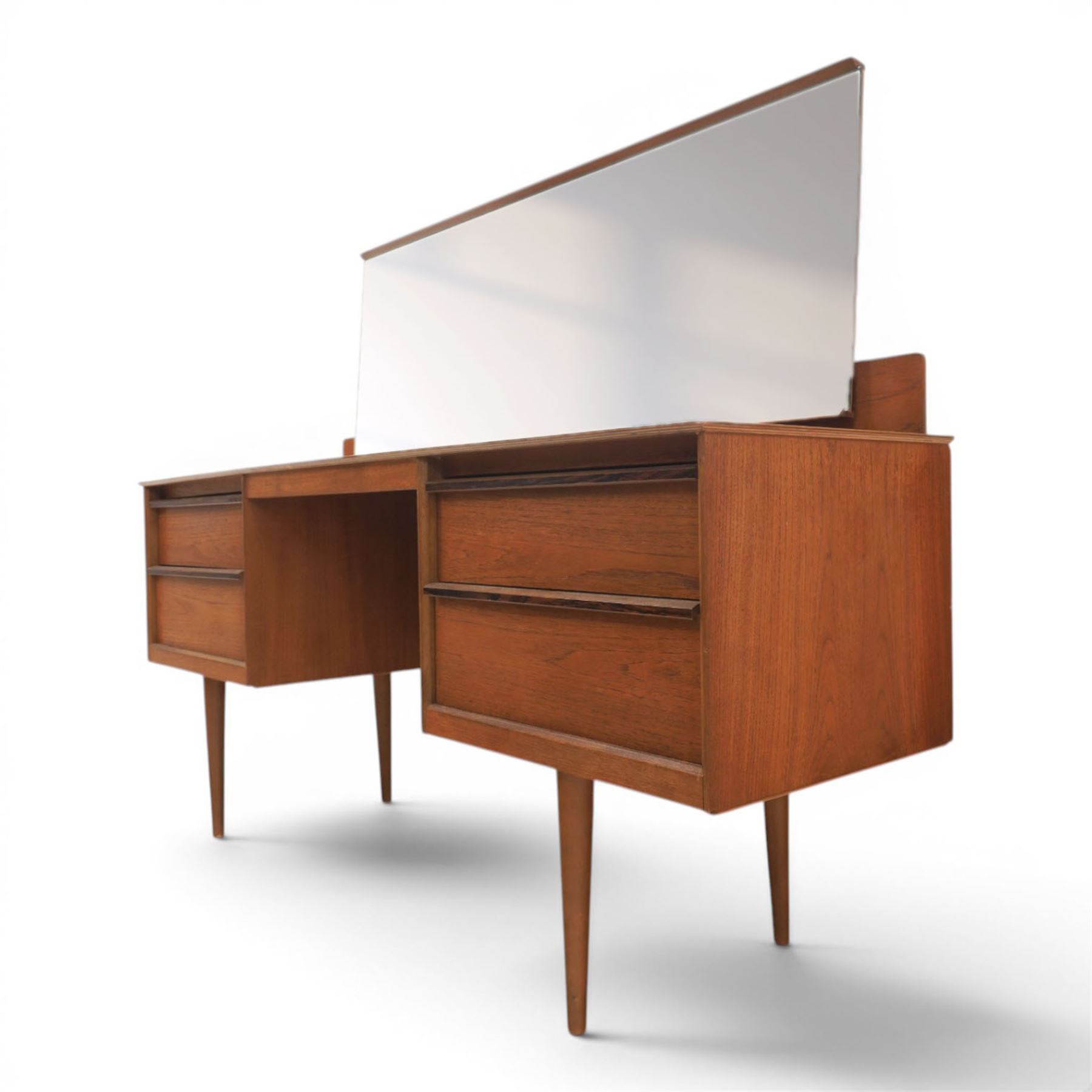Austinsuite - mid 20th century teak headboard with bedside cabinets and matching  mirrored dressing table, the headboard with floating single drawer bedsides raised on a single tapering support, the dressing table with attached tilting mirror, above rectangular top with kneehole and two banks of two drawers, raised on tapering supports

Headboard H 84cm, D 40cm, W 229cm, W between bedsides 151cm 
Dressing table H 113cm D 44cm, W 149cm, H to underside of dresser 61cm