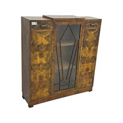 Art Deco burr walnut drinks cabinet, geometric central glazed astragal door enclosing two fixed shelves, flanked by symmetrical bookmatched veneered cupboards with drawers above 