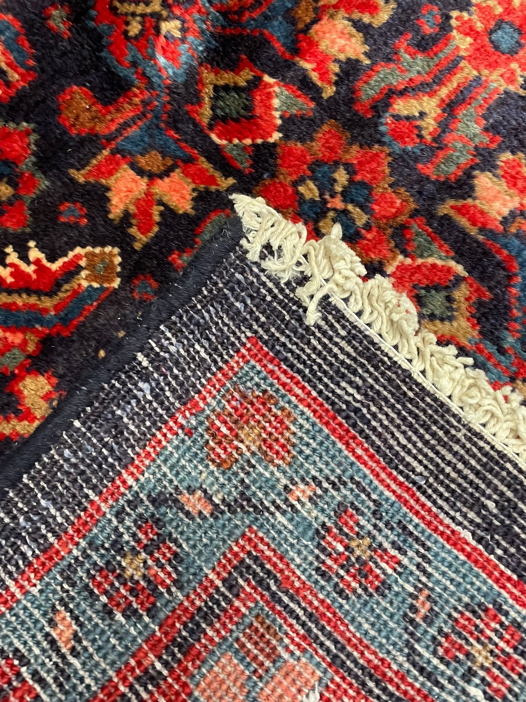 Persian indigo ground rug, the field decorated all over with floral Heratti motifs, crimson border with trailing stylised flower heads, within guard stripes