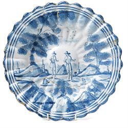 18th century Dutch Delft plate of fluted design decorated in blue and white with figures in a landscape D29cm and a Dutch Delft vase decorated in blue and white with oriental flowers H21cm (2)