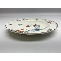 Mid 18th century Chelsea red anchor period plate, circa 1752-1754, hand painted in enamels in the Kakiemon palette with flowering peony and chrysanthemum issuing from rock work, and butterfly in flight above, the shaped rim detailed with conforming floral sprigs and butterflies within a iron red line border, with red anchor mark beneath, D22cm