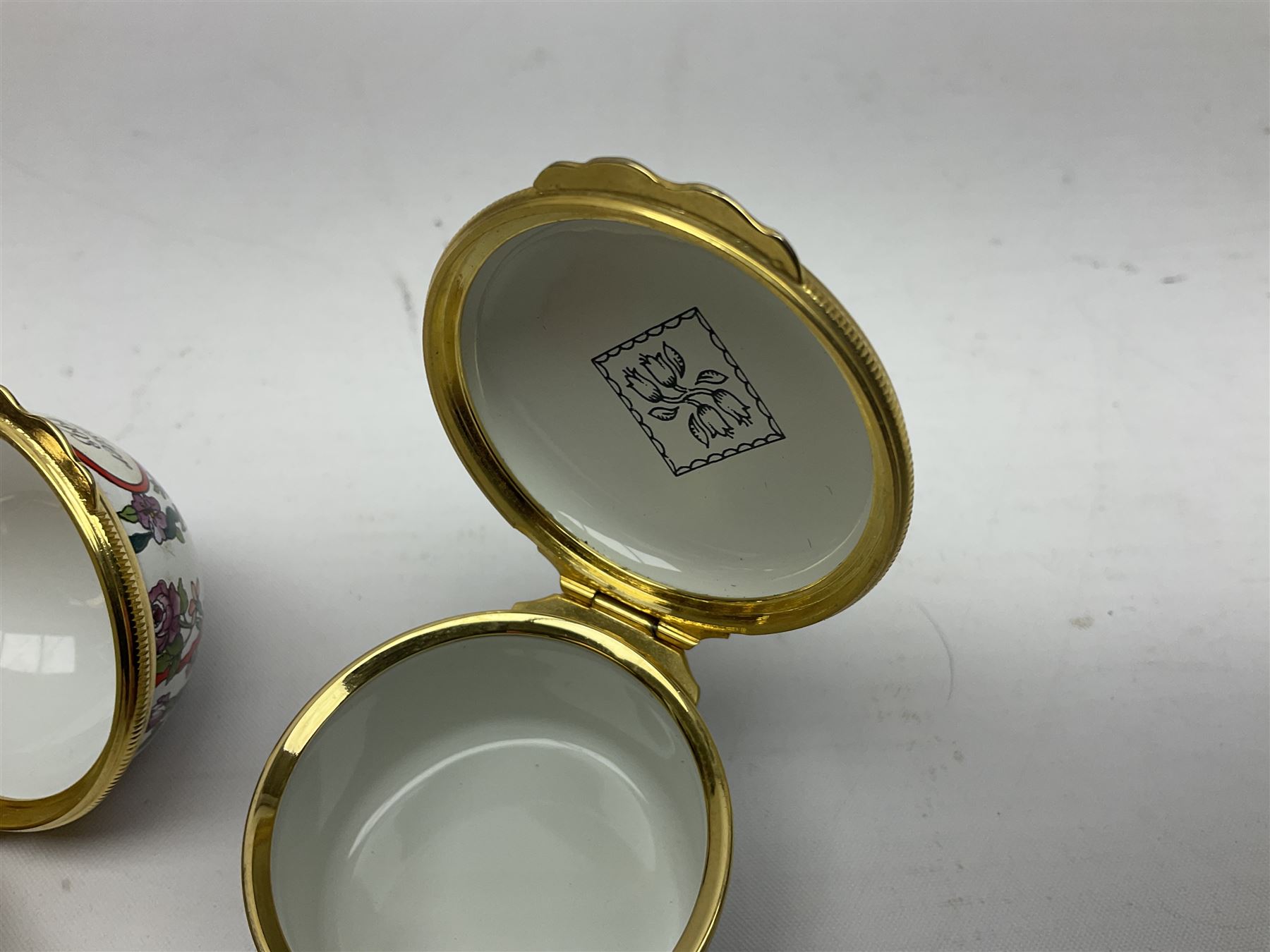 Halcyon Days bonbonniere, modelled as pink roses in a planter painted with a blue and white Japanese scene, together with five Halcyon Days enamel boxes, one a larger example depicting 'The Becket Casket' and four smaller boxes, including The 1993 Easter Egg, Happy Birthday and Statue of Liberty examples, all boxed, Becket Casket D8cm