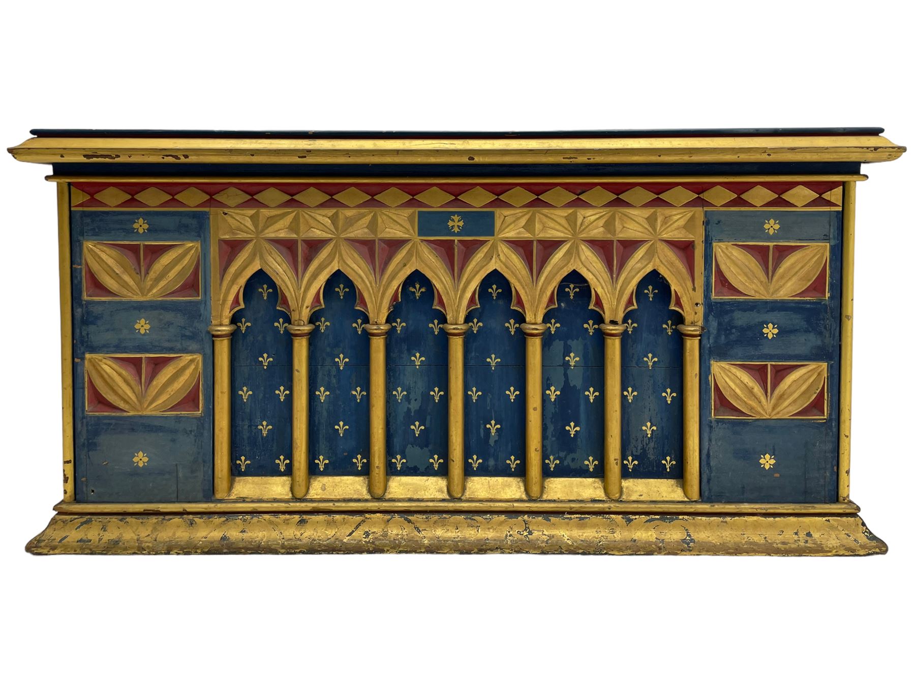 In the manner of William Burges - mid-to-late 19th century English Gothic Revival pine altar or console table, in blue and red paint with water gilding, the moulded rectangular top over six pointed arches with turned column supports, the front carved with a single row of lozenges and incised stylised motifs
