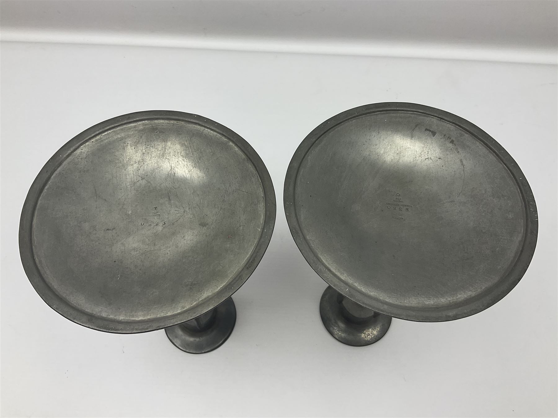 Pair of Solkets English pewter candlesticks, the bud shaped sockets raised upon three angular fin supports and a slightly domed circular base with cast stylised foliate decoration, H23cm