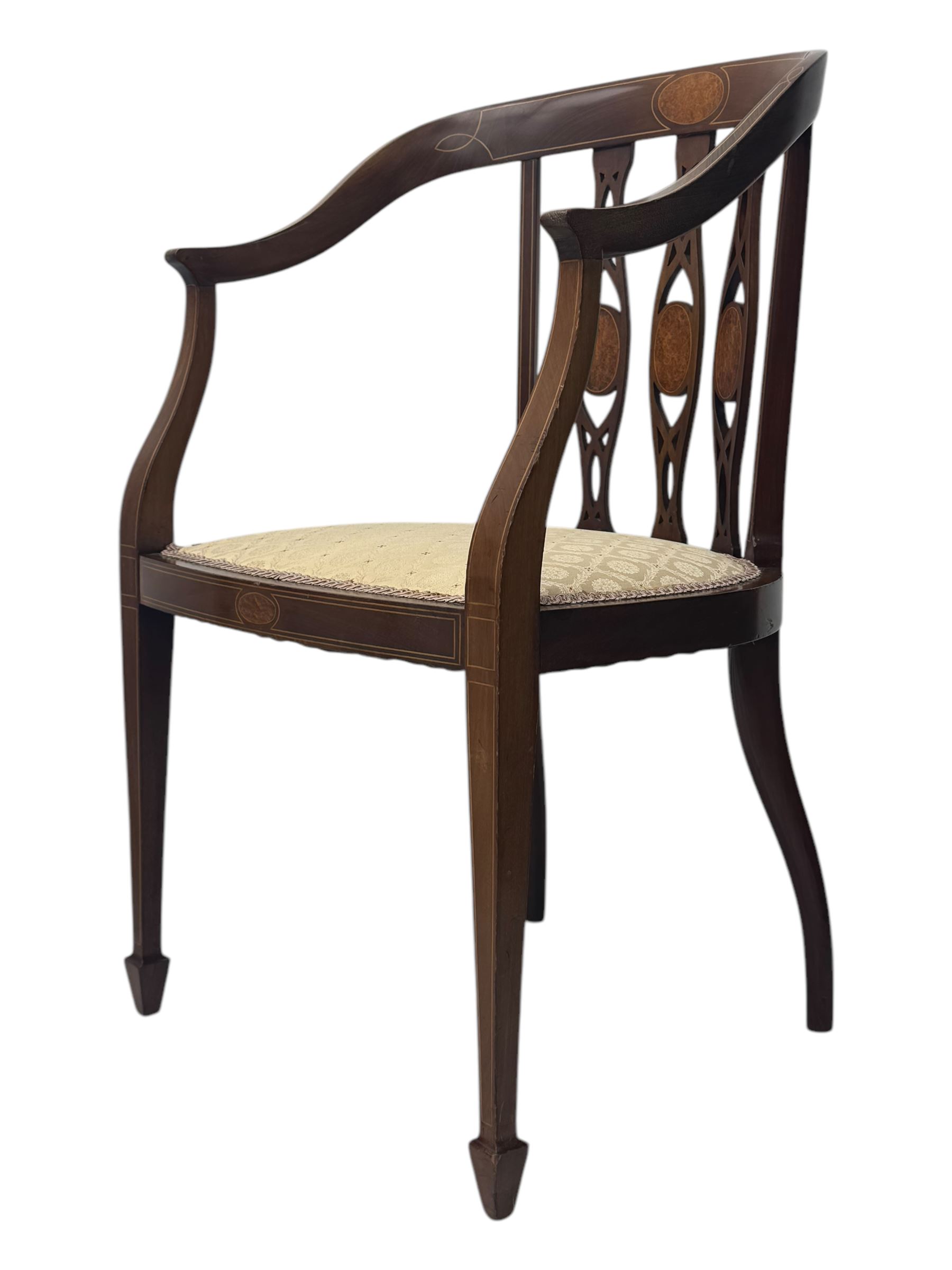 Pair of Edwardian mahogany tub chairs, curved top rail inlaid with oval marquetry panels, the backs with a pierced, elongated splat design featuring a central oval motif, the seats upholstered in cream fabric, on square tapering supports with spade feet
