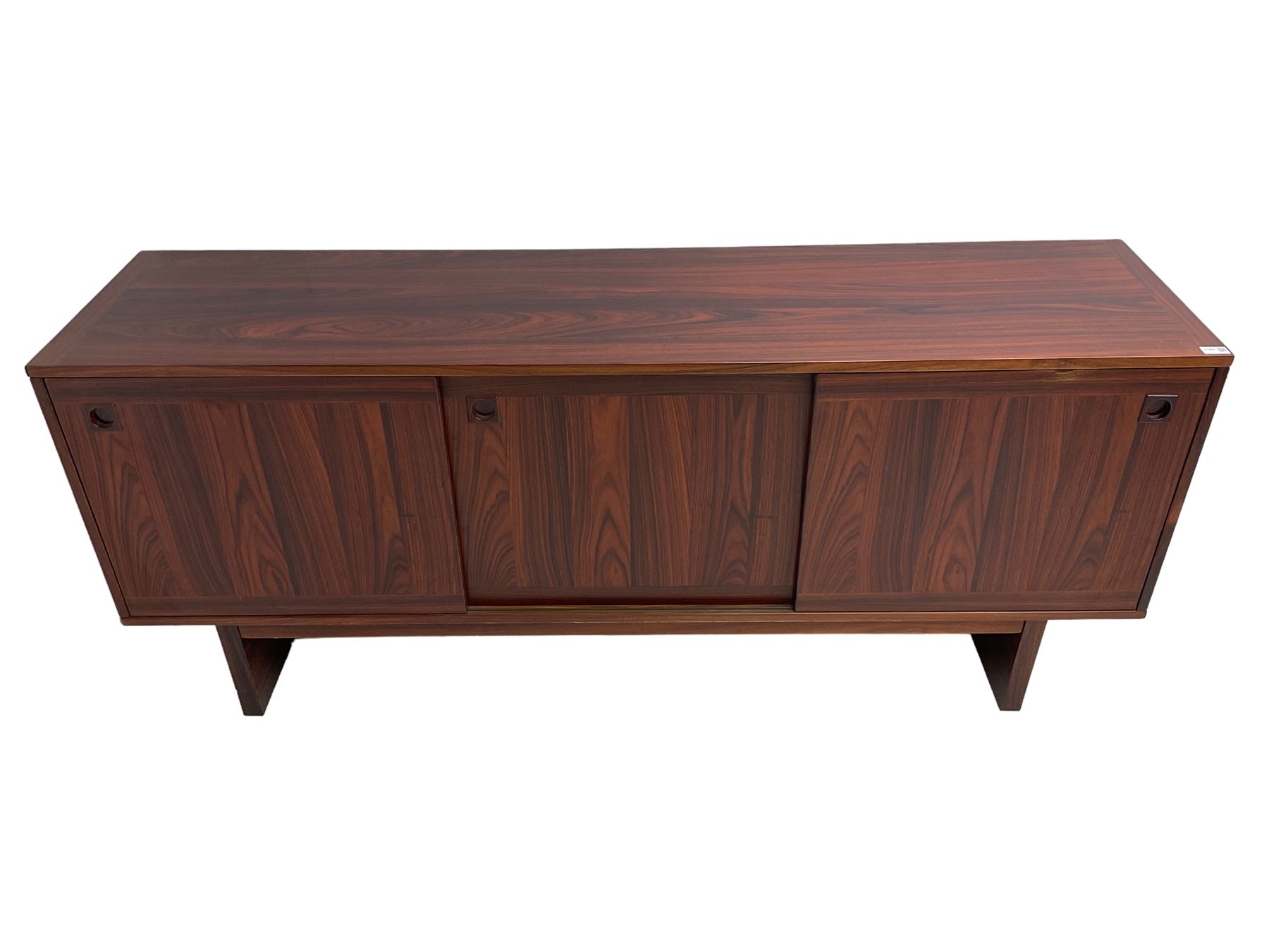 NH Chapman & Co Siesta - mid-20th century sideboard, fitted with three sliding doors, enclosing two drawers and shelves, raised on twin end supports