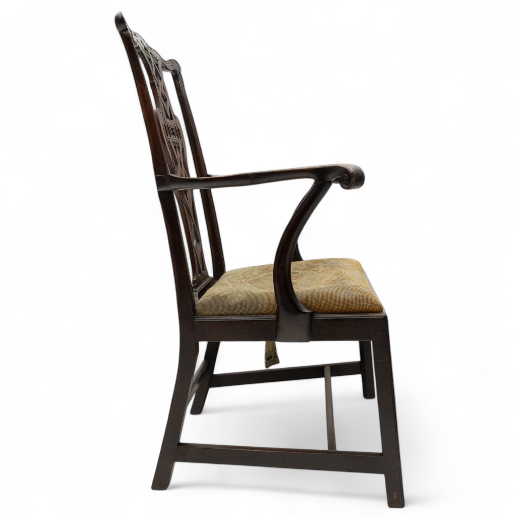 19th-century Chippendale Revival design mahogany oversized high-back armchair, serpentine crest carved top rail above pierced back splat with interlaced ribbon carving and geometric fretwork design, and outward scrolling arms above drop-in needlework seat on square chamfered legs 