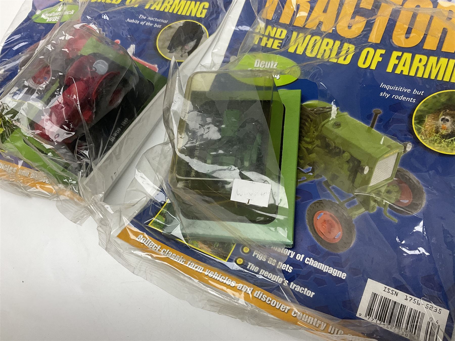 Eighteen issues of Tractors and The World of Farming magazine, together with sixty diecast tractors, all in original packaging, in three boxes 