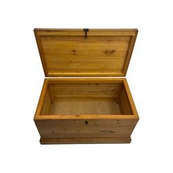 Contemporary polished pine blanket chest, the hinged planked lid with iron strap hinges and clasp fitting, plain boarded sides, fitted with blackened metal drop handles, on a moulded plinth base