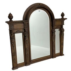 Late 19th century carved oak overmantle mirror, arched top with foliate carved edge and two turned acorn finials, triple bevelled plate front with carved figural pilasters decorated with fruit and trailing branch