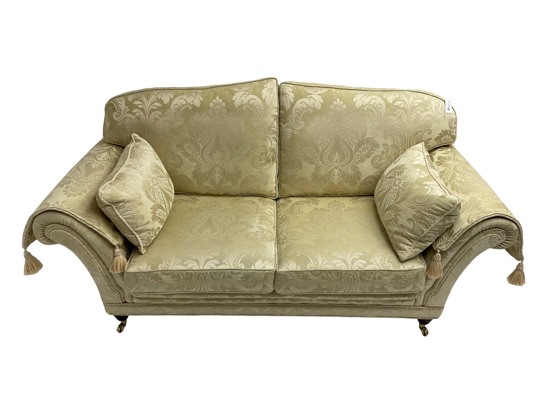 Steed Upholstery - two seat traditional shaped sofa, upholstered in cream fabric with scrolling foliate pattern, on turned front feet with brass castors, with side cushions and arm covers