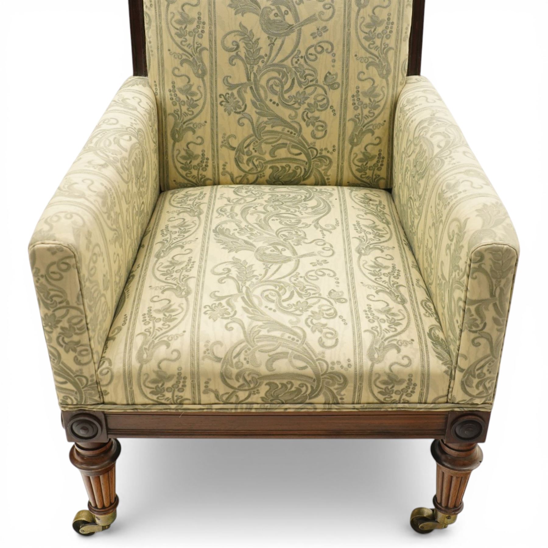 William IV rosewood framed library armchair, squared form with green on ivory ground upholstery, moulded lower seat rail with applied roundels over reeded supports, terminating to brass cups and castors