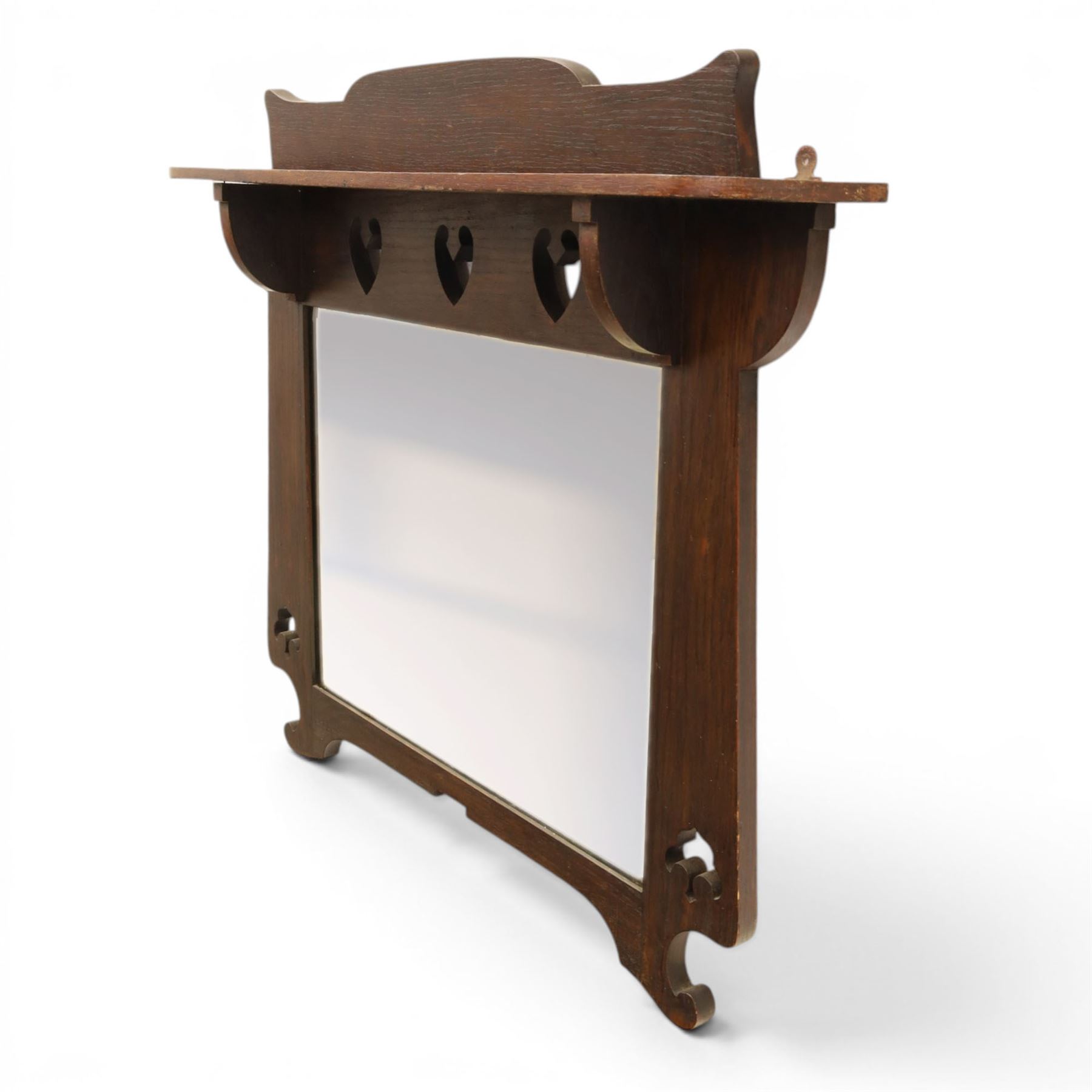 Arts and Crafts oak wall mirror, rectangular mirror plate within shaped frame, raised shelf with shaped back and pierced heart detail, bracket supports and shaped lower rail
