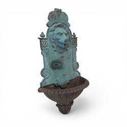 Antique cast iron wall fountain, cartouche cresting rail over a lion mask spout, with scroll and floral decoration over a scalloped basin, in rustic turquoise painted finish with rusted patina