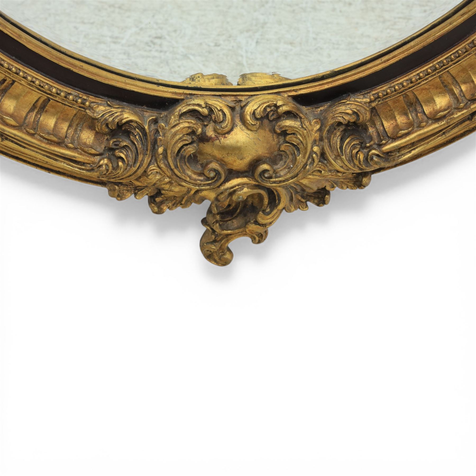 Rococo Revival style gilt composition oval wall mirror, moulded oval frame with fluted and beaded bands enclosing a bevelled mirror plate, the outer frame with acanthus leaf and scroll carved cresting to each side
