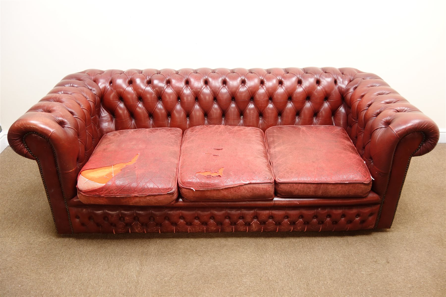 Three seat Chesterfield sofa upholstered in deep buttoned ox blood