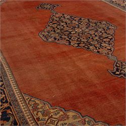 North West Persian Tabriz hand-knotted carpet, salmon field with central elongated lozenge medallion intricately filled with scrolling arabesques and palmettes, framed by stylized corner spandrels within a broad indigo main border  of bold palmettes and floral vinery between multiple guard stripes, rendered in tones of terracotta, sage green, and soft ivory, with cotton fringe ends 