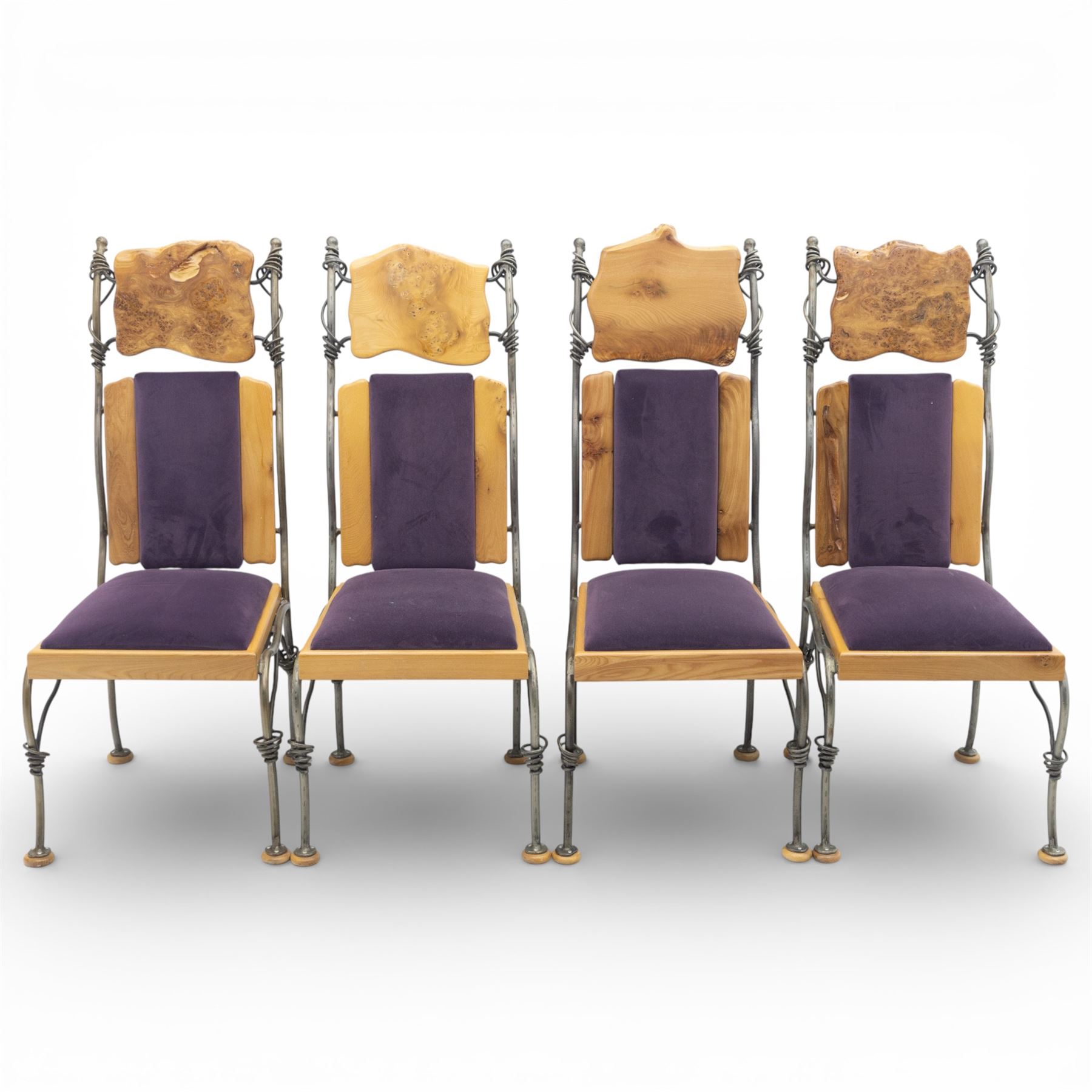 Paul Hodgkiss Designs of Glasgow - contemporary shaped elm dining table with wrought iron base; with set ten (8+2) matching high-back dining chairs, table of organic form above an elaborate wrought iron supports, with central elm stretcher, the chairs with en suite with matching wrought iron work burred elm headrest, purple velour upholstery with drop in seat     

Table: W 102cm, L 243cm, H 74cm
Chairs: W 56cm, D 52cm, H 130cm