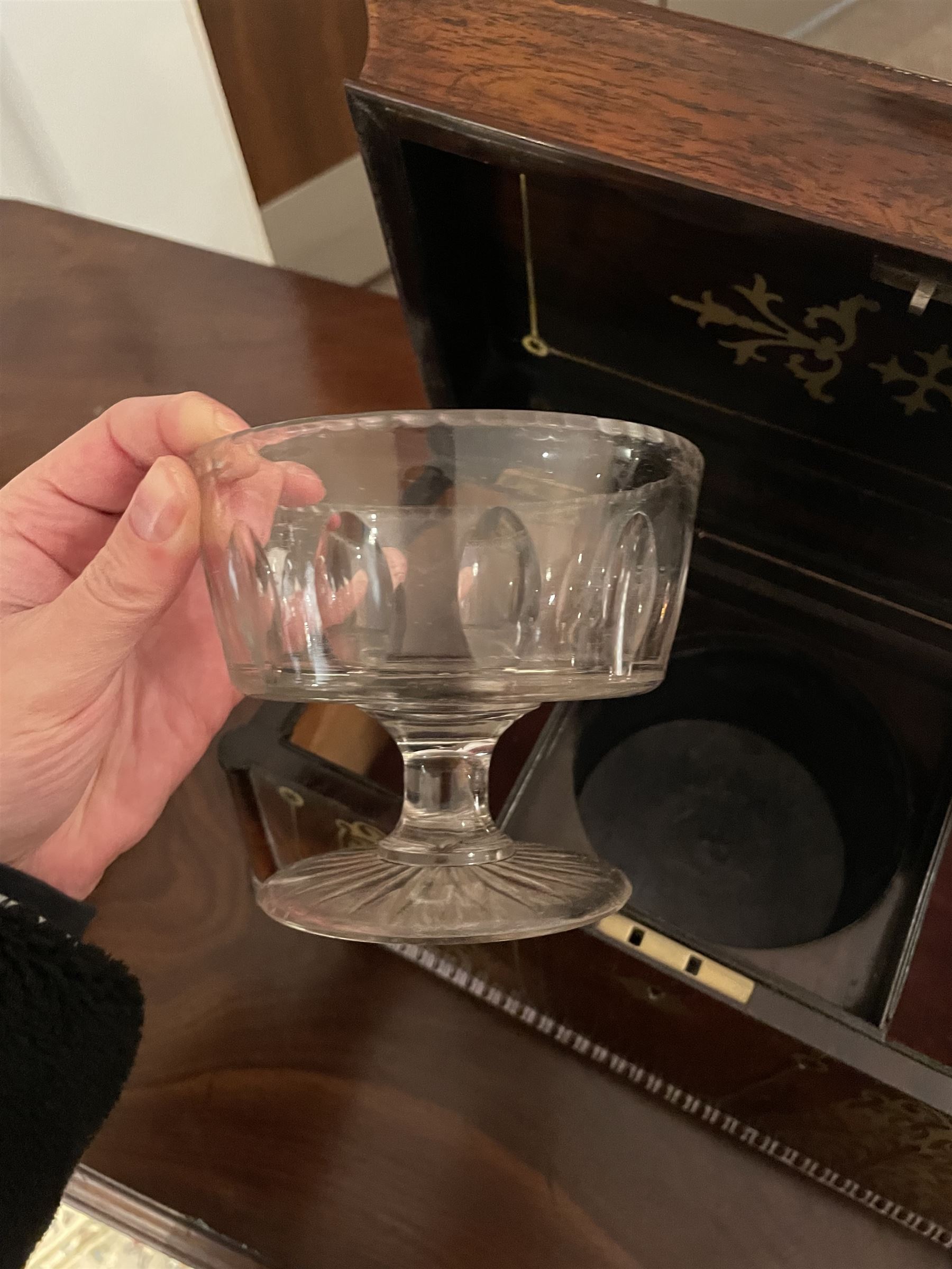 Early 19th century rosewood and brass inlaid tea caddy, of sarcophagus form, the front and hinged opening cover inlaid with brass scrolling panels, opening to reveal a compartmented interior with twin removable boxes with conforming inlaid brass detail to the hinged covers and zinc lining to the interiors, flanking a later glass mixing bowl, the whole upon four turned cylindrical feet, H21cm W36cm D20cm