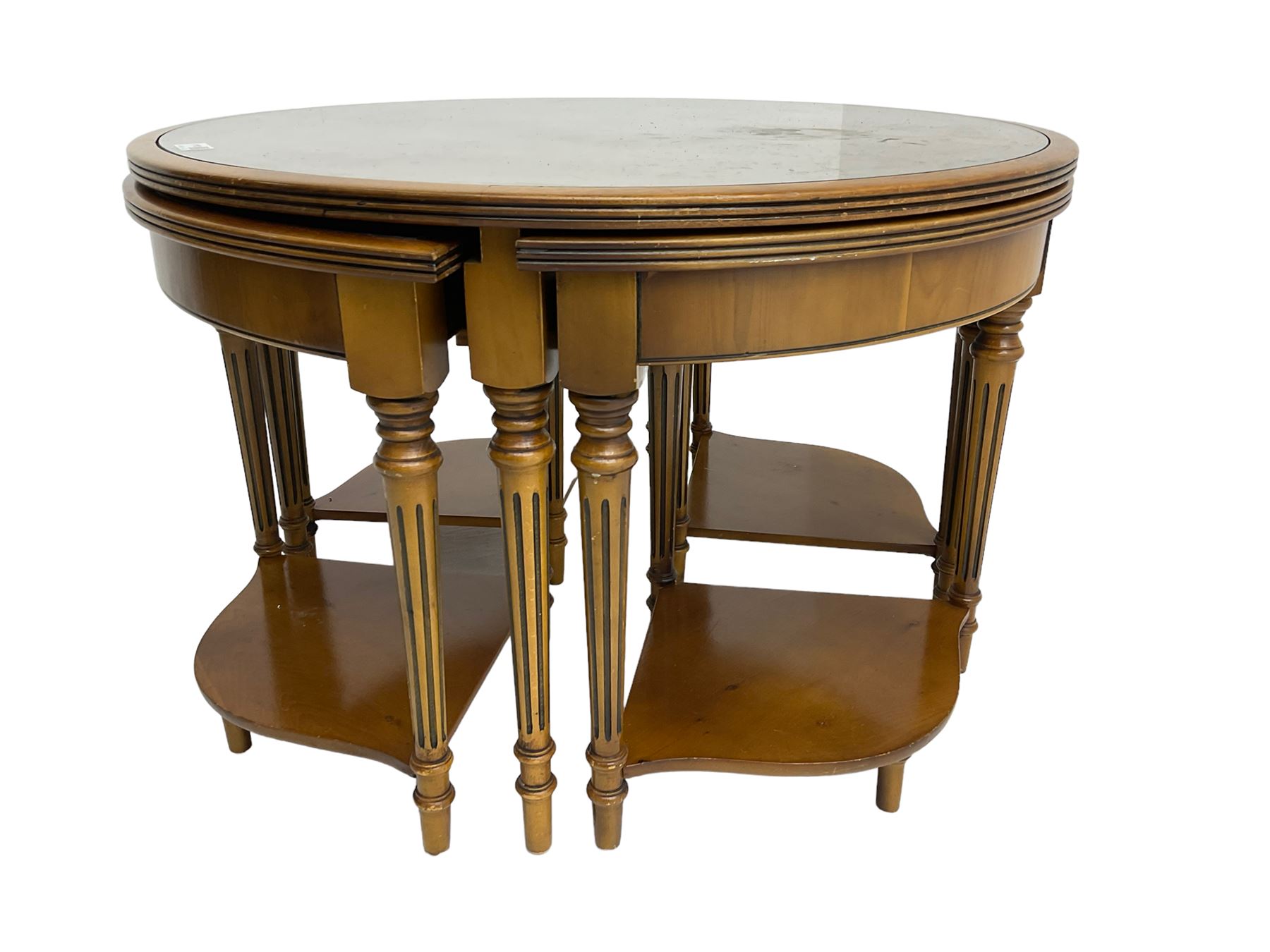 Yew wood circular coffee table with four nesting tables, inset leather and glass tops, on turned and fluted supports