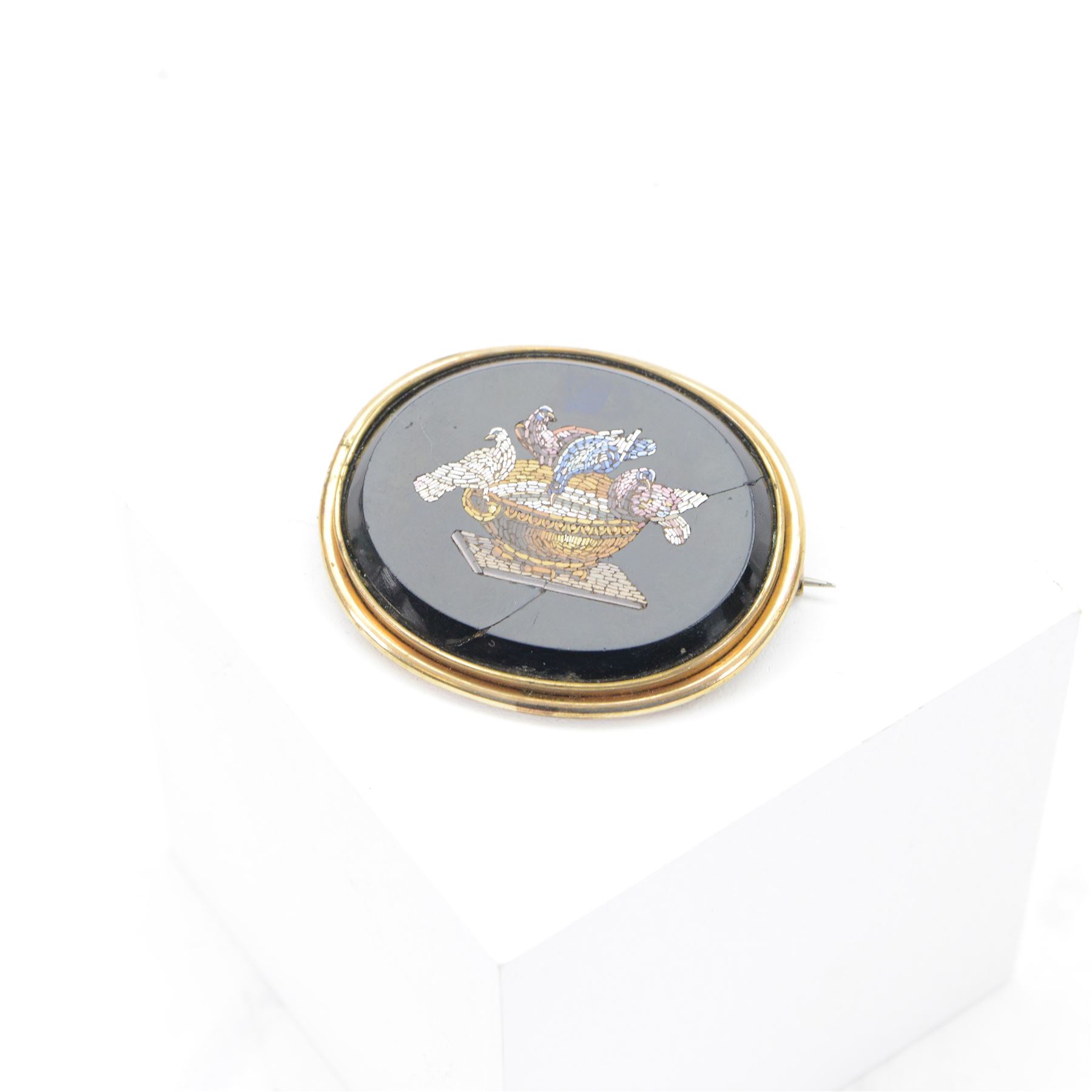 Micro mosaic brooch of Pliny Doves, the oval black panel set with a micro mosaic of doves drinking from a water bath, within a gilt metal setting 