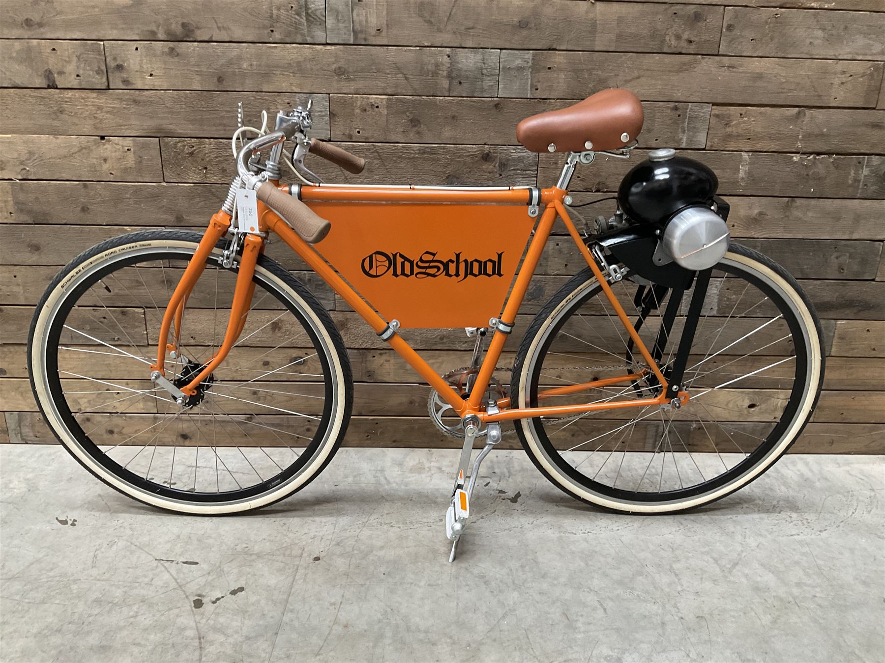 Fully restored vintage advertising bicycle with 2 stroke petrol engine, orange frame, tan leather seat