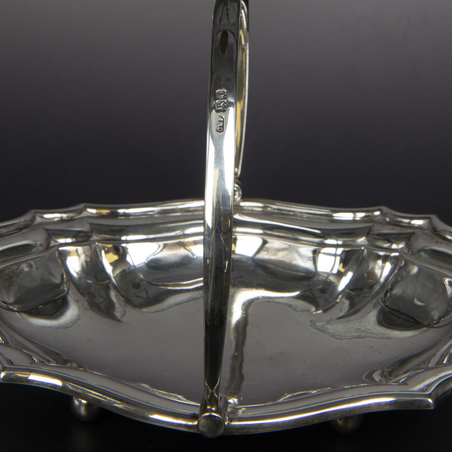 Early 20th century silver swing handled basket, of oval form with shaped rim and upon four bun feet, hallmarked C W Fletcher & Son Ltd, London 1918