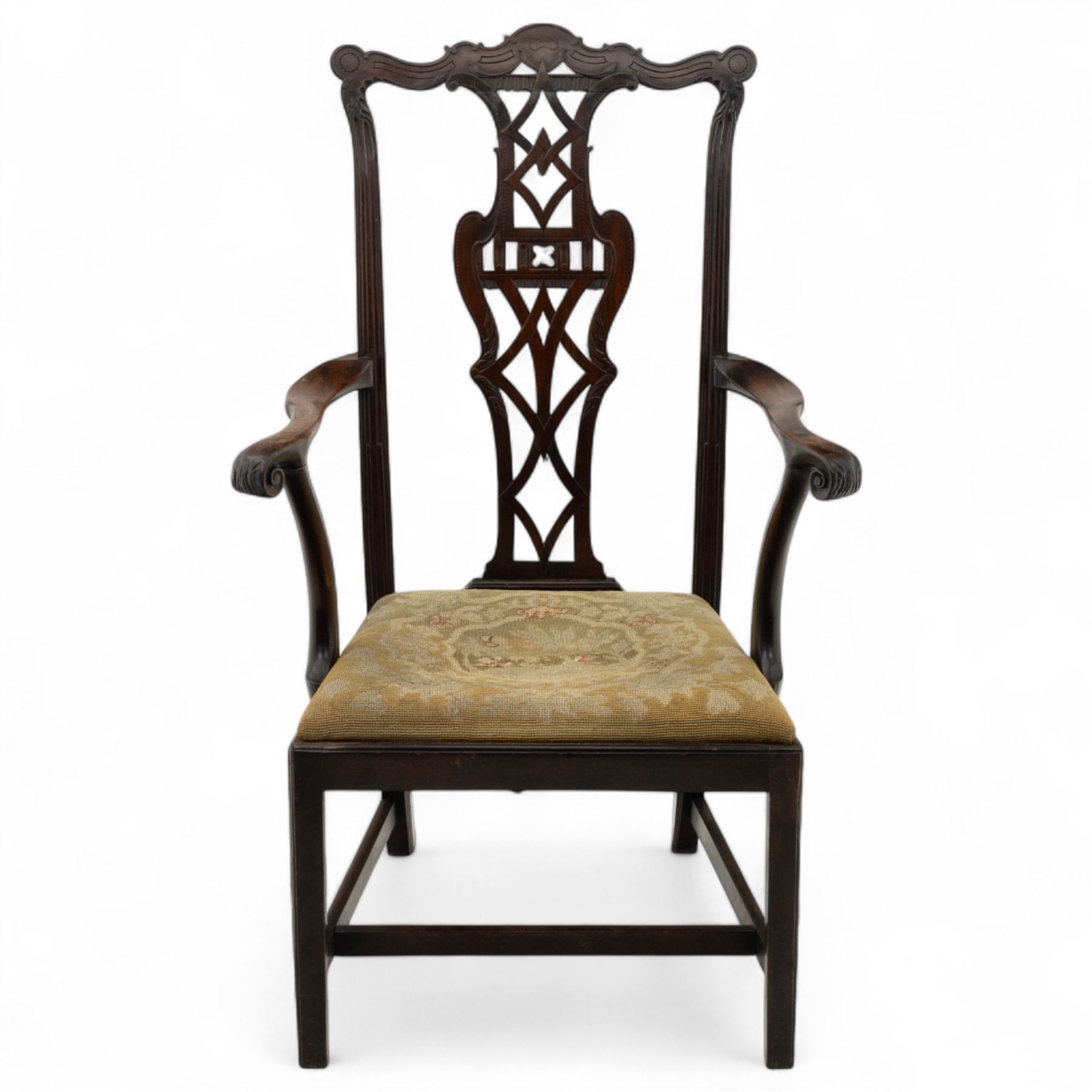 19th-century Chippendale Revival design mahogany oversized high-back armchair, serpentine crest carved top rail above pierced back splat with interlaced ribbon carving and geometric fretwork design, and outward scrolling arms above drop-in needlework seat on square chamfered legs 