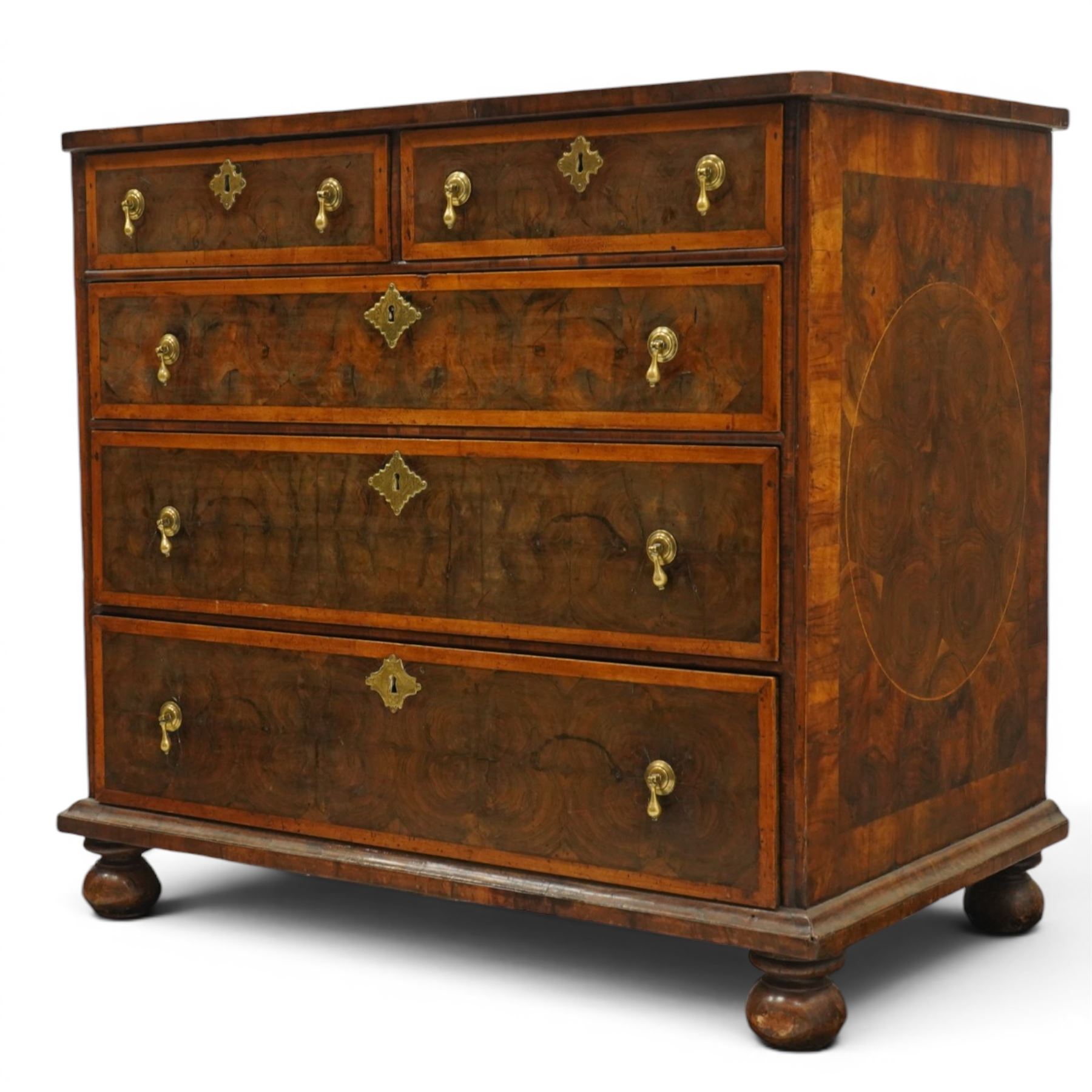 William & Mary period laburnum and walnut oyster-veneered chest, the rectangular top with canted corners and walnut banded edge, profusely decorated with oyster veneer and fruitwood stringing in concentric circles, fitted with two short over three long drawers with fruitwood banding, each fitted with original pressed brass escutcheons and pull handles, lower moulded edge over original bun feet