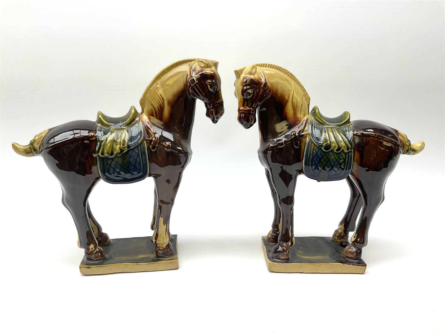 A pair of glazed pottery Tang style horses, each with impressed marks beneath, each approximately H25.5cm. 