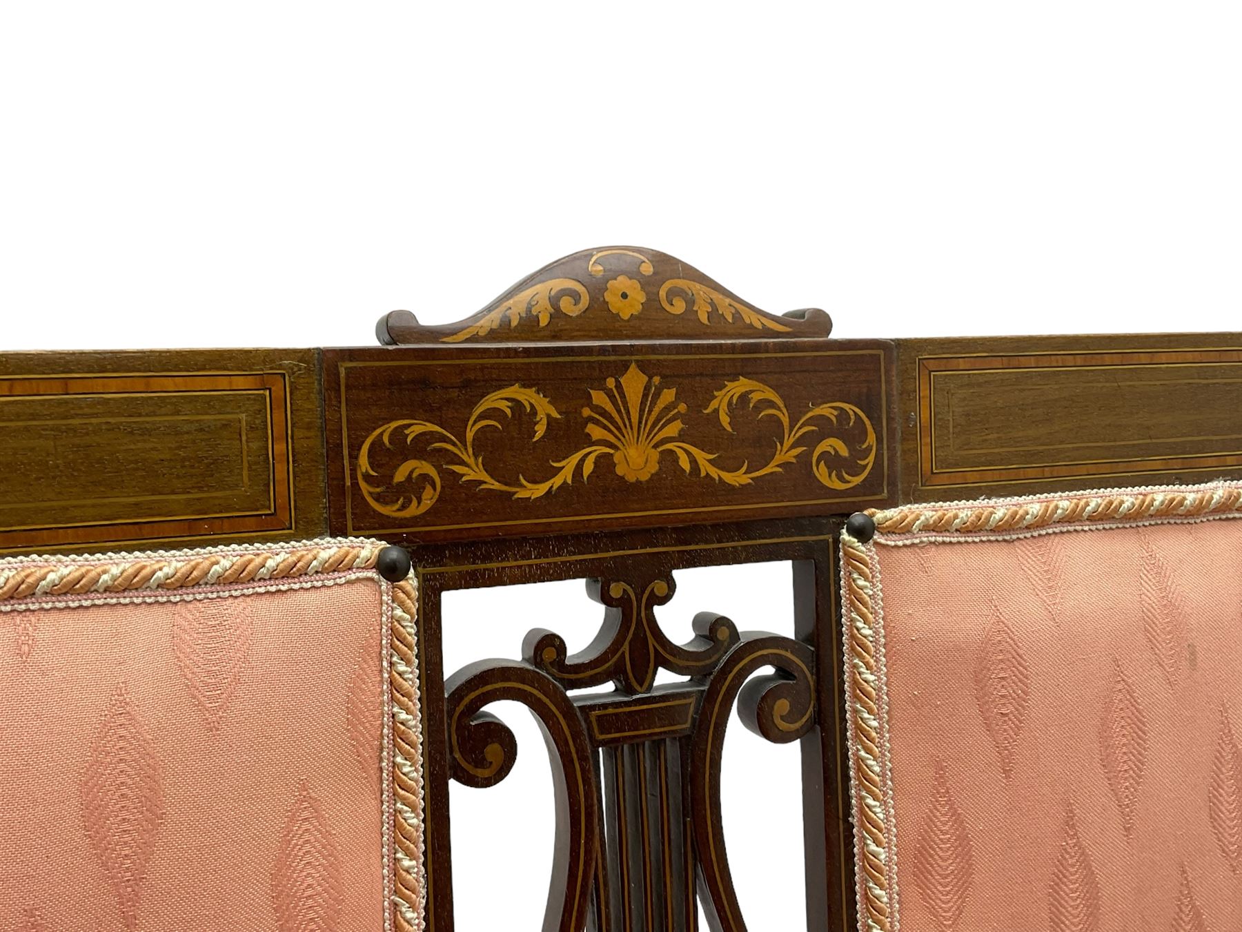 Edwardian inlaid mahogany two-seat settee or hall bench, the cresting rail inlaid with satinwood banding and boxwood stringing, central panel inlaid with scrolled leafy branches over pierced and carved lyre back, upholstered in peach fabric with repeating pattern, scrolled down sweeping arms, on square tapering supports with spade feet 