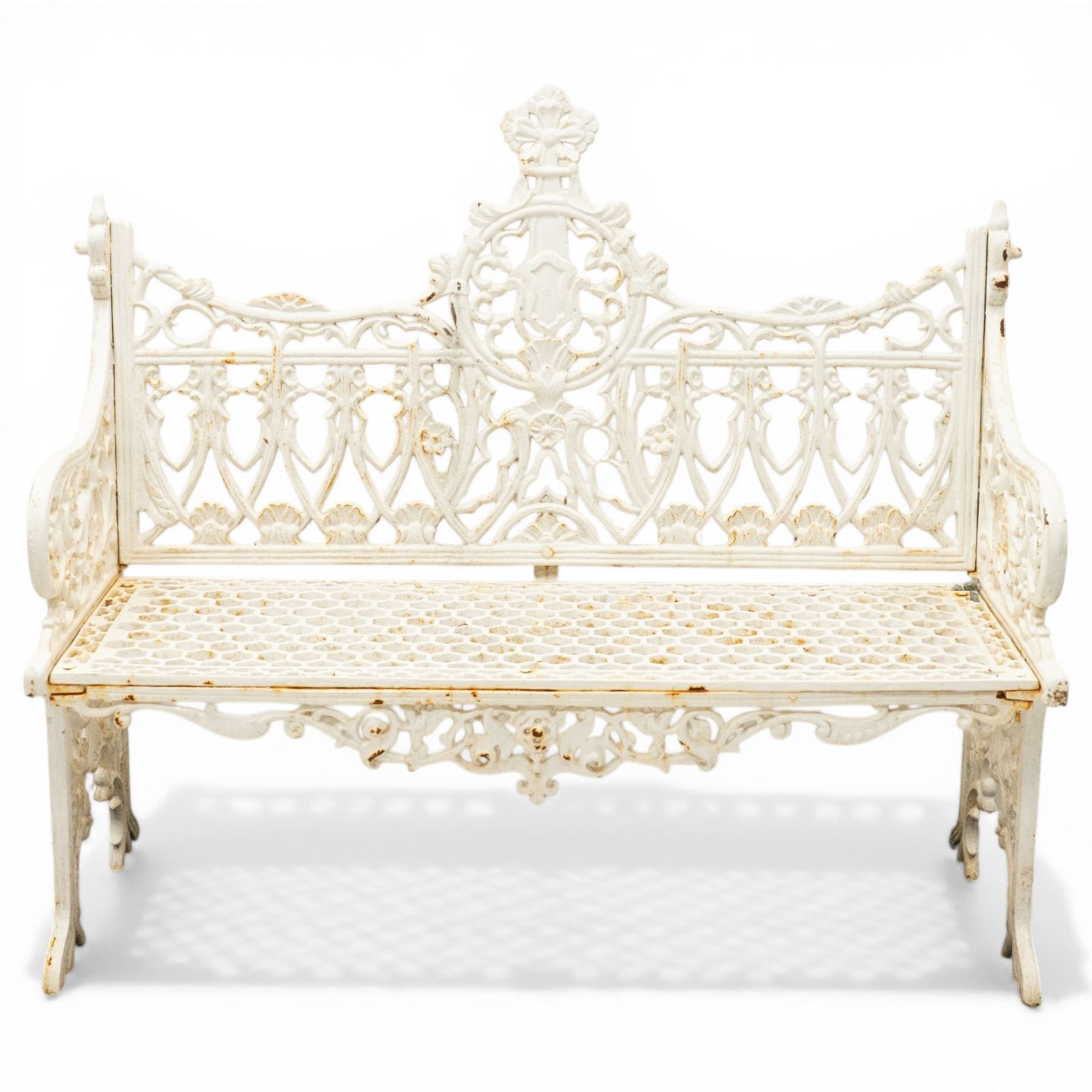 Victorian revival heavy cast iron garden bench, ornate back rest with scrolls, floral motifs and central crest, pierced lattice seat, curved arms and decorative legs, painted in antique white, in the Gothic Coalbrookdale style
