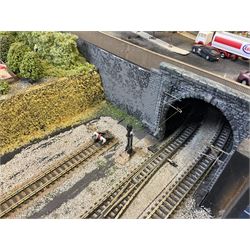 'Z' gauge continental scenic layout with folding legs, various loops of track and sidings with overhead cables, buildings including water tower, tunnels, roads with motor vehicles and figures, trees, haven with boats, backdrop diving wall hiding control units 150 x 50cm