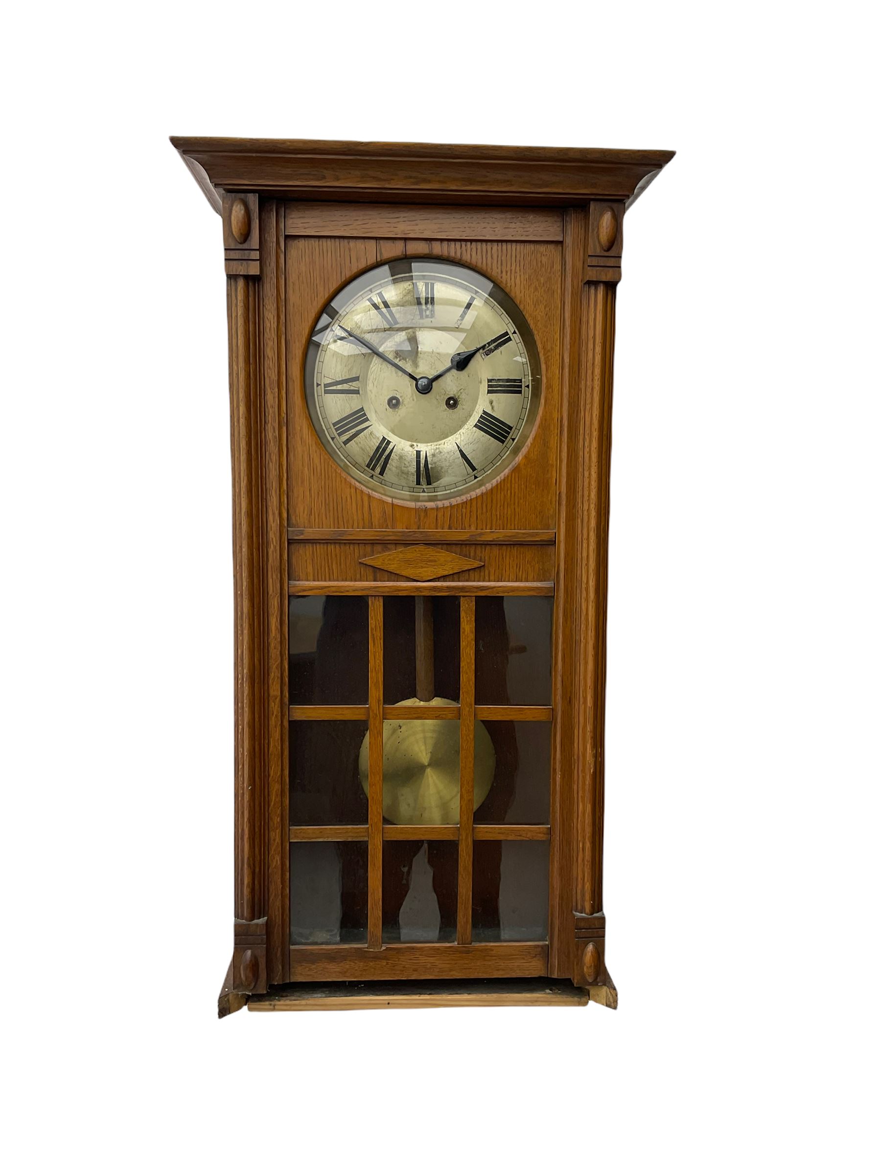 A 1930’s German eight-day spring driven wall clock by Philipp Hass & Sohne striking the hours and half hours on a gong, with an eight-inch silvered dial with a spun brass bezel, Arabic numerals, minute track and steel spade hands, in a flat-topped oak case with full length door and applied mouldings, nine glazed panels with a visible spun brass pendulum. With key.                                   