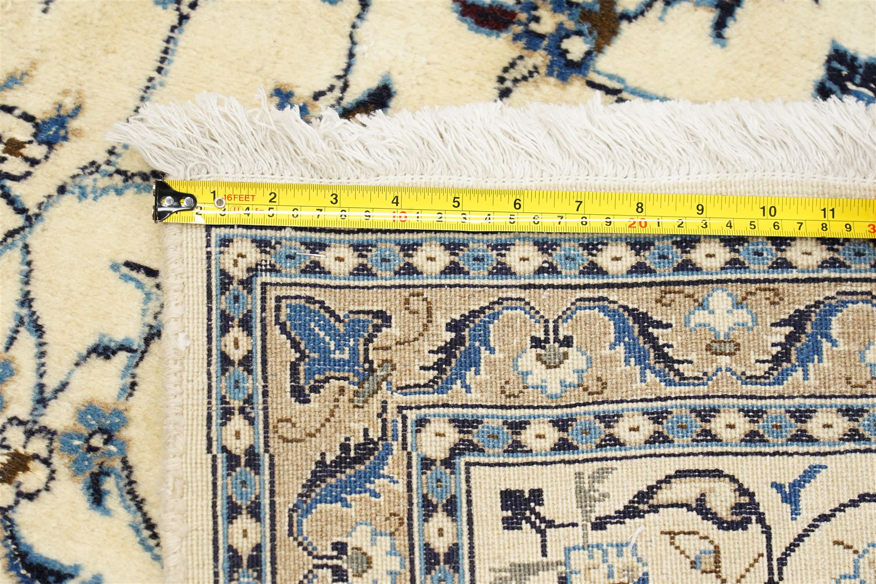 Central Persian Nain hand-knotted carpet, ivory field with central radiating medallion, issuing an all-over design of scrolling vines, palmettes, and delicate floral sprays with conforming spandrels, enclosed by a foliate border, framed by multiple guard stripes, with cotton fringe ends 