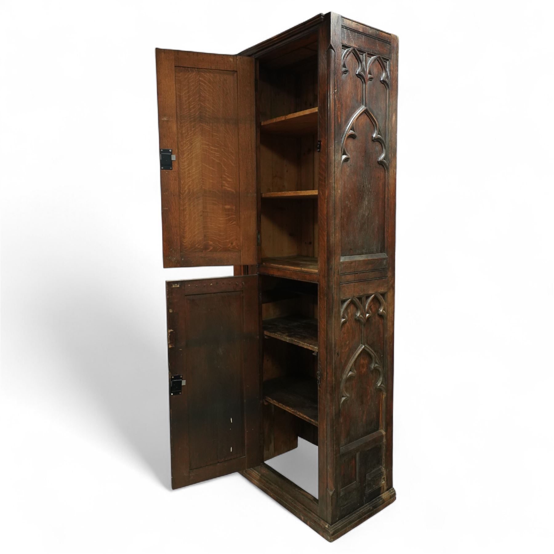 19th century Gothic Revival oak Sacristy vestment cupboard of tall proportions, fitted with two ecclesiastical trefoil moulded panelled doors enclosing four shelves, flanked by a chamfered corner, the side panelled and moulded with matching sacristic architectural mouldings, on skirted base