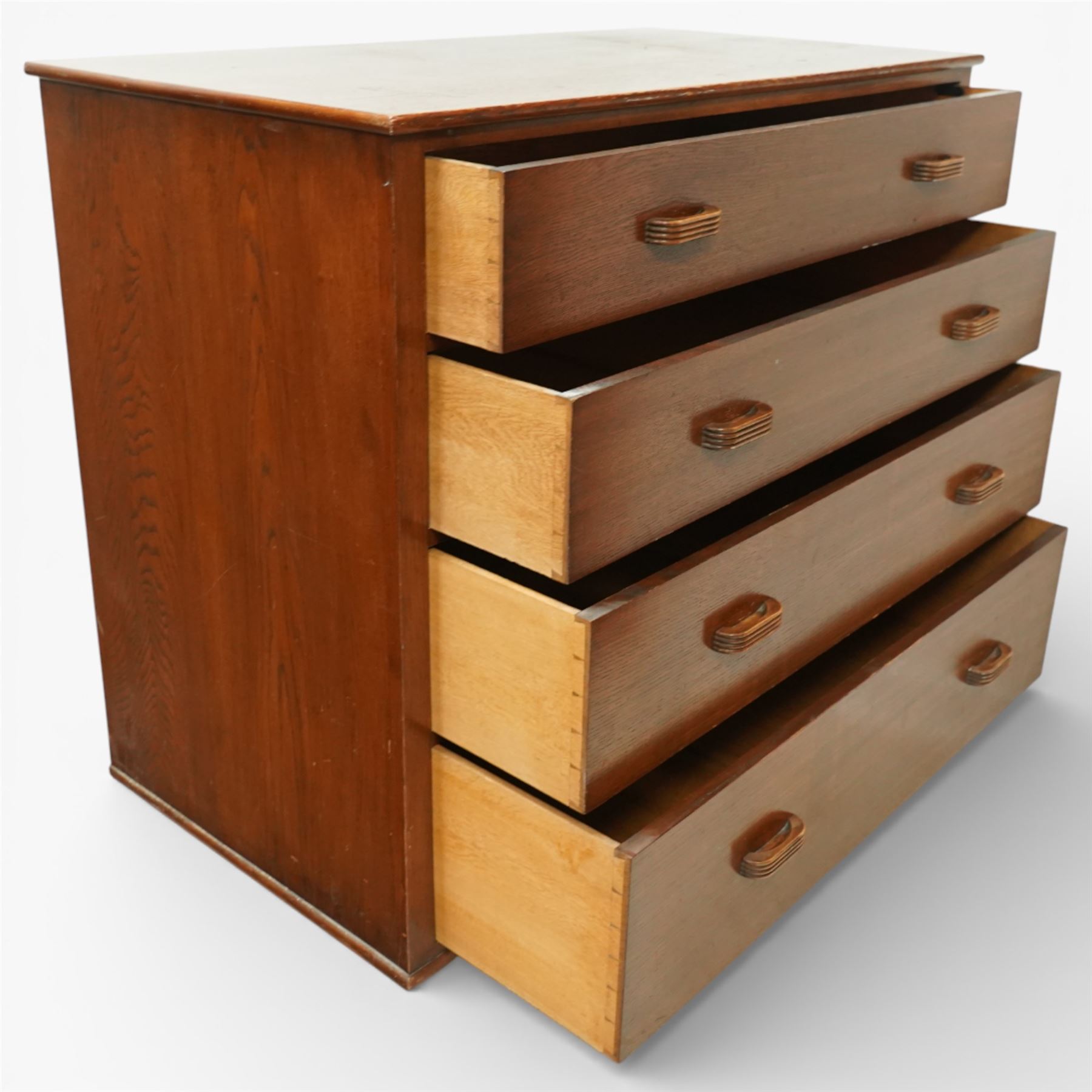 Mid 20th century oak chest of drawers, rectangular top with gently rounded front edge over four graduating drawers fitted with recessed ribbed wooden handles, plain drawer fronts, raised on an integral plinth base