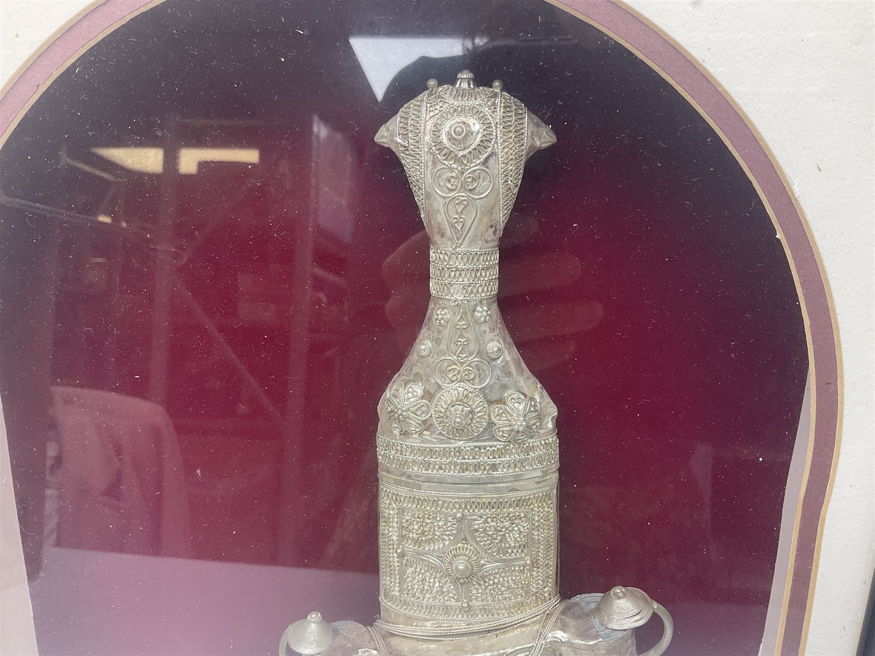 20th century silver Khanjar dagger from Oman, heavily decorated with filigree throughout, dome shaped pommel and waisted grip, the sheath with fastening rings, with miniature curved dagger accessory, housed in red lined glazed box frame, L38cm