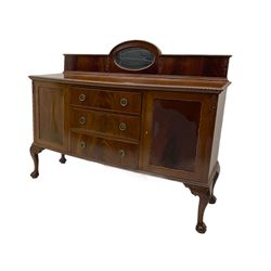 Early 20th century mahogany bow-fronted sideboard, raised back with oval inset mirror, the top with gadroon carved edge, fitted with two cupboards and three drawers, raised on scrolled carved cabriole supports with ball and claw feet
