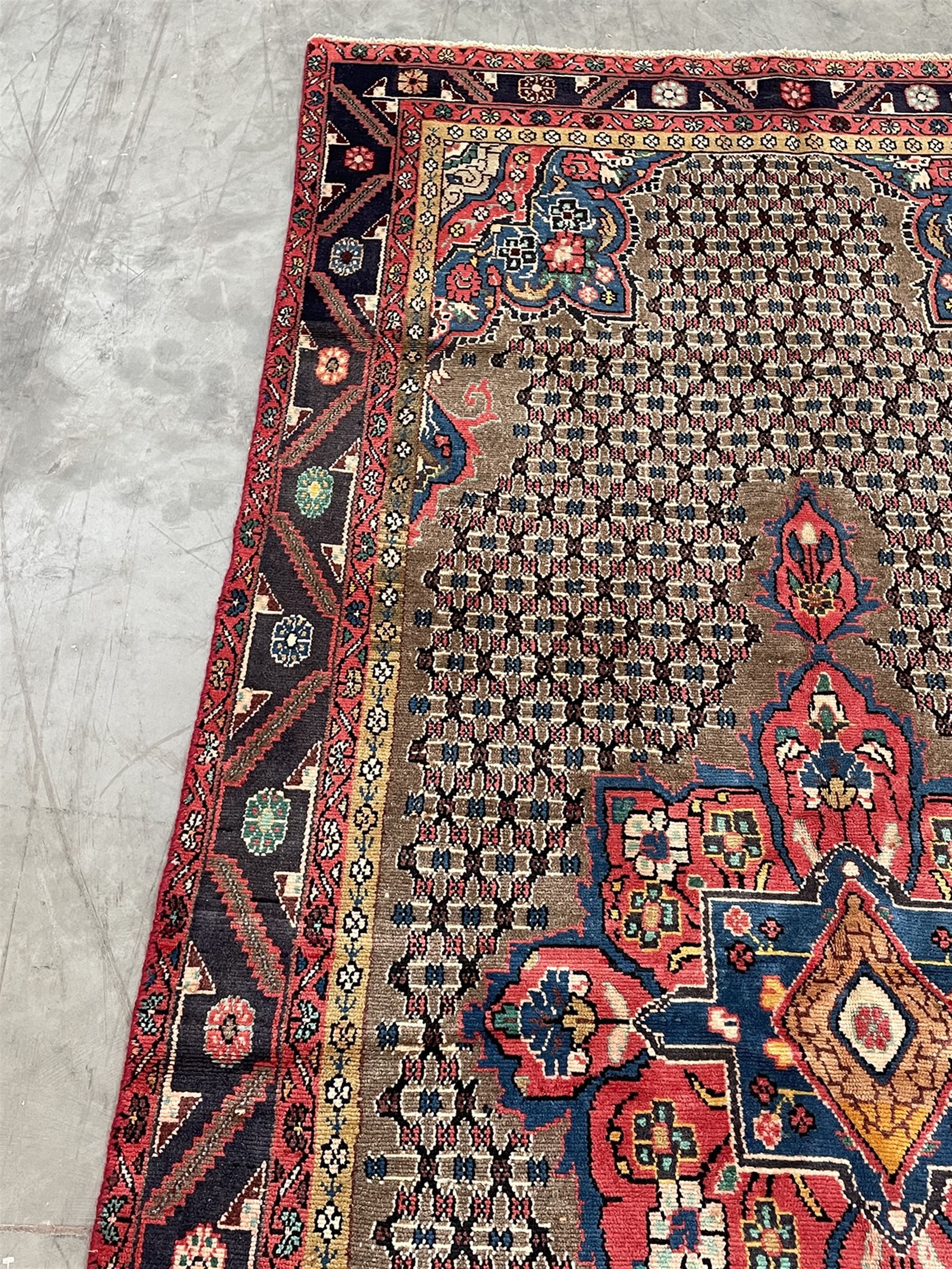 Persian Hamadan rug, the rosette pole medallion on a pale field decorated with stylised motifs, the blue band border decorated with stylised flower heads