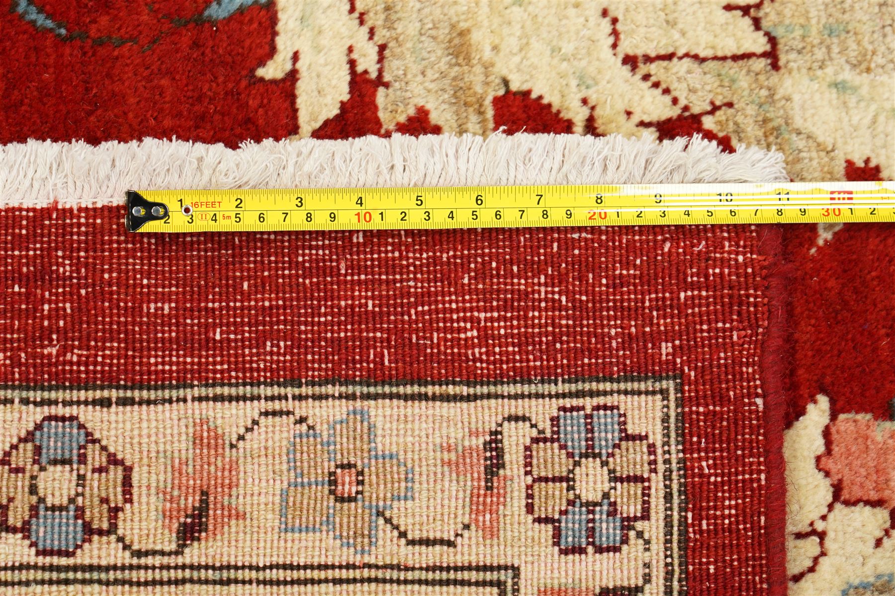 West Persian Sarough hand-knotted carpet, rich madder red field, decorated with stylized palmettes angular vinery and floral sprays within multiple borders of ivory ground and scrolling foliate decoration, with cotton fringe ends 