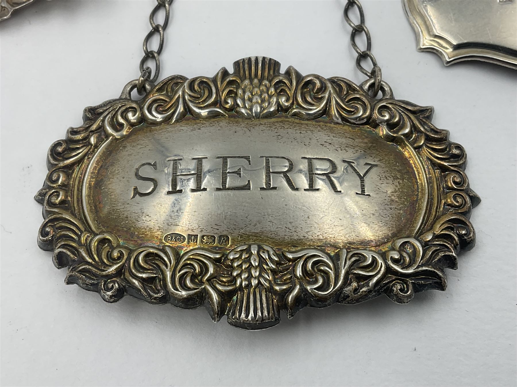 Five modern silver decanter labels, to include two sherry examples, embossed with scrolls and fruits, hallmarked W I Broadway & Co, Birmingham 1991 & 1997, a similar claret example, hallmarked S J Rose & Son, Birmingham 1973, and two plain shaped port and burgundy examples, hallmarked C Robathan & Son, Birmingham 1997 and A Haviland-Nye, London 1968