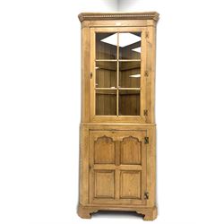 Oak corner cabinet, projecting cornice, dentil frieze, single glazed door enclosing two glass shelves above bottom unit, single fielded door enclosing fitted interior 
