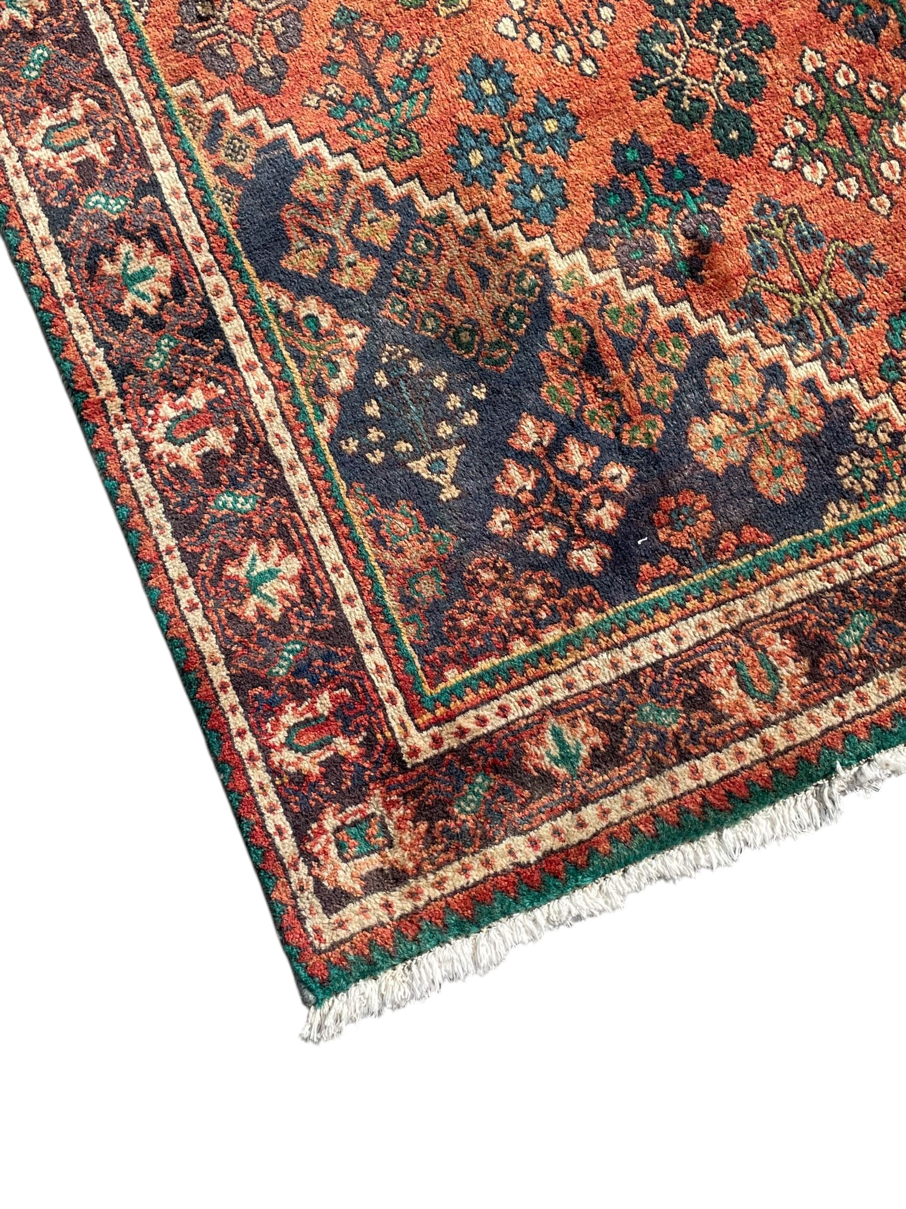 Persian Joshaghan rust ground rug, stepped lozenge medallion surrounded by repeating foliate lozenge motifs, the border decorated with stylised plant motifs, within geometric guard stripes
