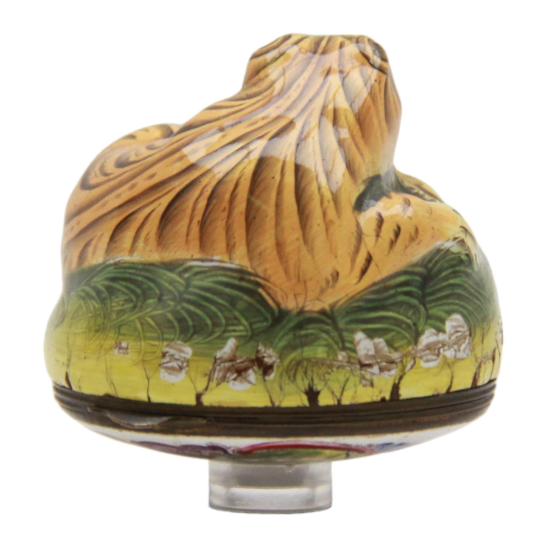 Rare 18th century Birmingham enamel bonbonniere, circa 1760, modelled as a grinning tiger laid upon a grassy sgraffito mound, the base decorated with a lion hunting scene after Antonio Tempesta, within a polychrome scroll surround, H5.5cm D6cm

