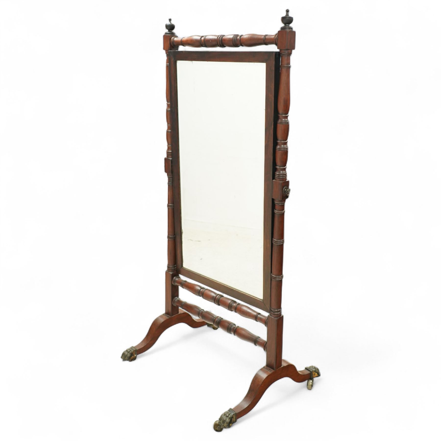 Late 19th-century Regency-style mahogany cheval mirror, rectangular mirror plate within turned uprights and turned cross stretchers supported on down-swept legs terminating in brass paw castors 