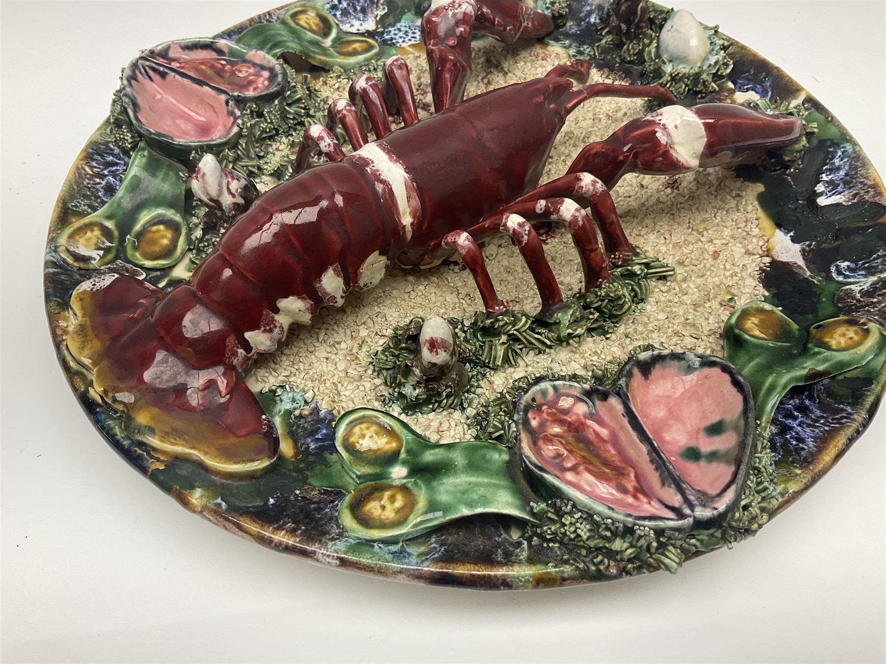 Two 20th Century Portuguese Palissy style Majolica wall plates, one depicting a crab, the other a lobster each to the centre modelled in relief surrounded by encrustations and shells, both with impress marks beneath, D34cm