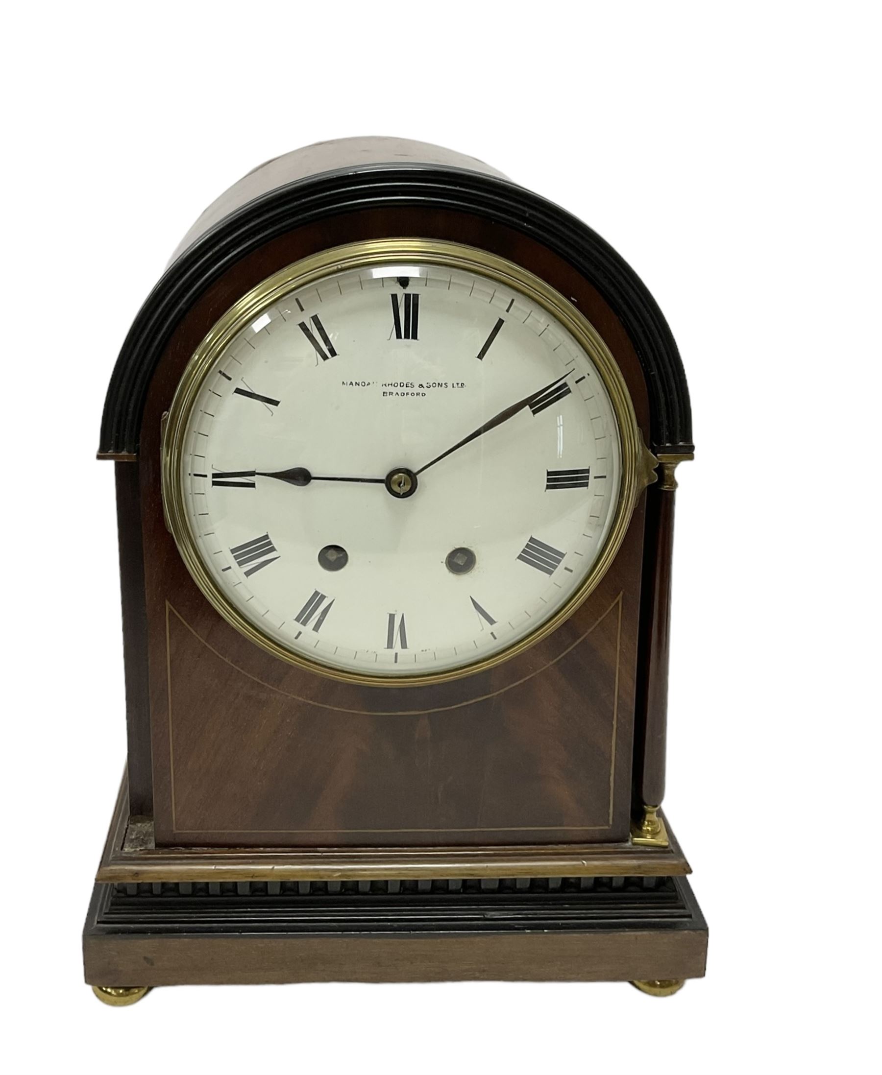 Manoah Rhodes & Son of Bradford, - Edwardian mahogany domed top mantle clock with a French 8-day movement striking the hours and half hours on coiled gong, case with inlaid stringing and raised on brass button feet, convex enamel dial with Roman numerals and steel spade hands. With pendulum and key.